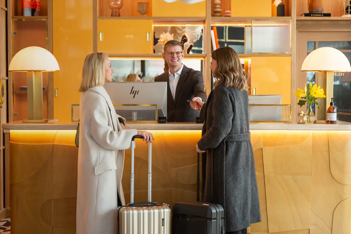 two women standing in the hotel reception with a male receptionist