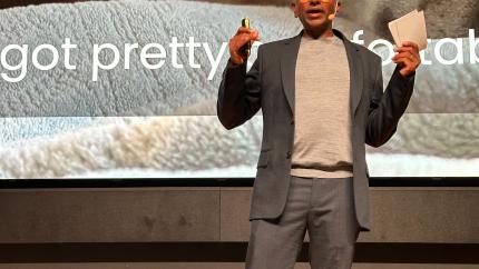 person on stage with a presentation in the background talking about AI