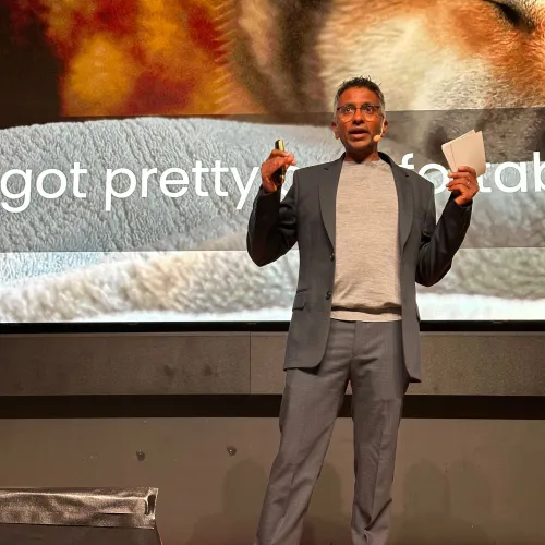 person on stage with a presentation in the background talking about AI